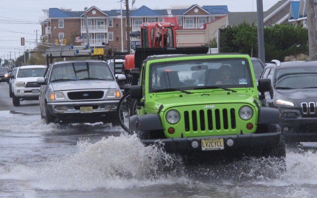Foto Archivo, Octubre de 2019  autos cruzan una intersección inundada en la entrada de Long Beach Island en Ship Bottom, Nueva Jersey. En 2021, el estado está lanzando una campaña para que los residentes documenten las inundaciones causadas por las mareas en su vecindario.