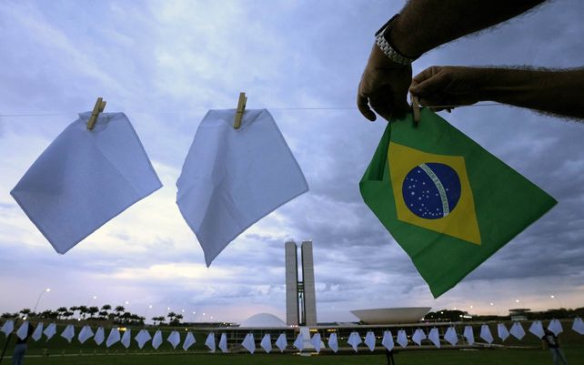 Pañuelos blancos que representan a personas que han muerto de COVID-19 en Brasil cubren un campo como parte de una protesta contra las políticas de salud del gobierno fuera del Congreso en Brasilia, Brasil, el lunes 18 de octubre de 2021.