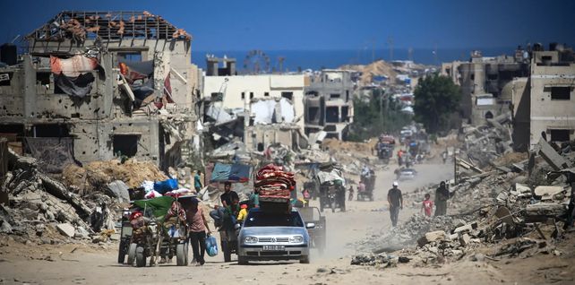 Los palestinos caminan y conducen junto a los edificios destruidos durante los bombardeos israelíes en el sur de la Franja de Gaza en medio del conflicto entre Israel y el grupo militante palestino Hamas, Khan Younis, Gaza. Fotografía: Eyad Baba/AFP/Getty Images
