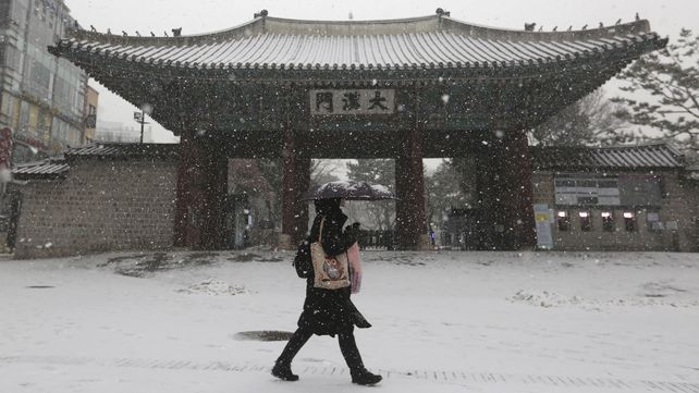 Una mujer pasa por la puerta principal del Palacio Deoksu durante el temporal de nieve en Seúl