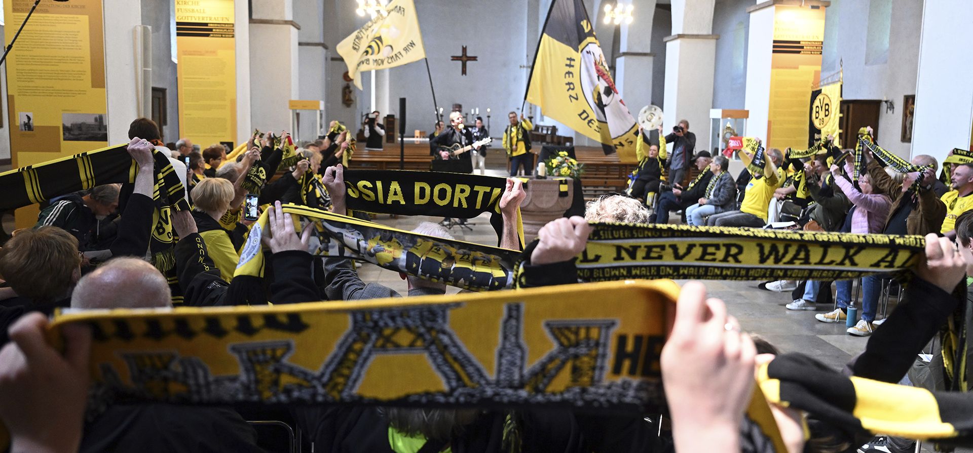 Aficionados del Dortmund sostienen sus bufandas durante un servicio en la iglesia fundadora del BVB para rezar por que el equipo gane el título de la Bundesliga alemana, en Dortmund, Alemania, el viernes 26 de mayo de 2023. El Dortmund logrará su primer título de la Bundesliga si vence al Mainz en un partido decisivo este sábado. (Federico Gambarini/dpa vía AP) Aficionados del Dortmund sostienen sus bufandas durante un servicio en la iglesia fundadora del BVB para rezar por que el equipo gane el título de la Bundesliga alemana, en Dortmund, Alemania, el viernes 26 de mayo de 2023. El Dortmund logrará su primer título de la Bundesliga si vence al Mainz en un partido decisivo este sábado. (Federico Gambarini/dpa vía AP)