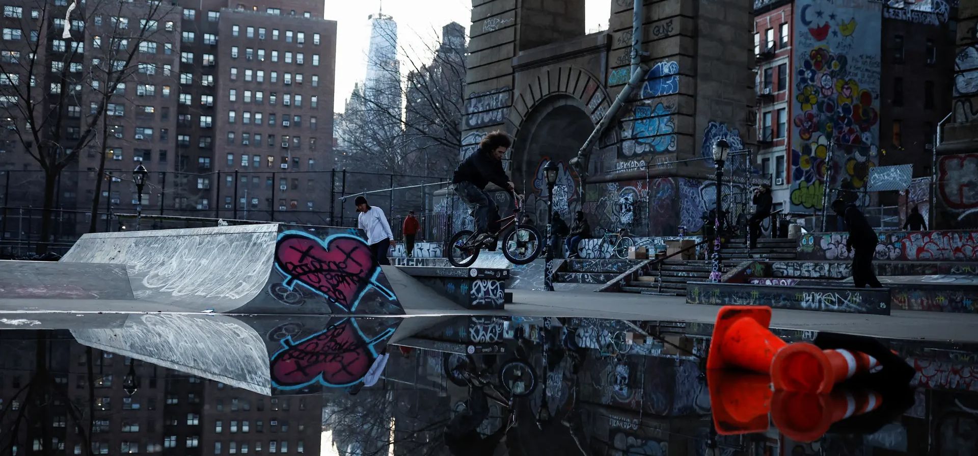 Reflejos en el agua mientras un ciclista y patinador usan el parque de patinaje LES Coleman bajo el puente de Manhattan, Nueva York, Estados Unidos. Fotografía: Amanda Perobelli/Reuters