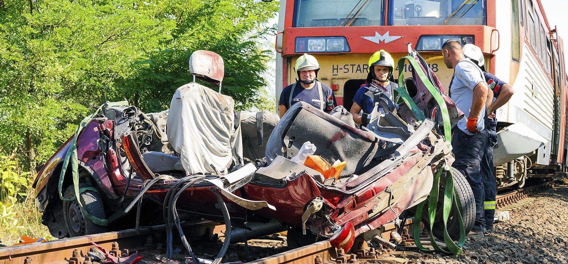 Bomberos peritan una escena donde un vehículo fue destrozado por un tren de pasajeros, cerca de Kunfeherto, en el sur de Hungría, el lunes 5 de septiembre de 2022. La policía húngara dice que siete personas murieron después de que un tren chocó con un vehículo en un cruce ferroviario en sur de Hungría.