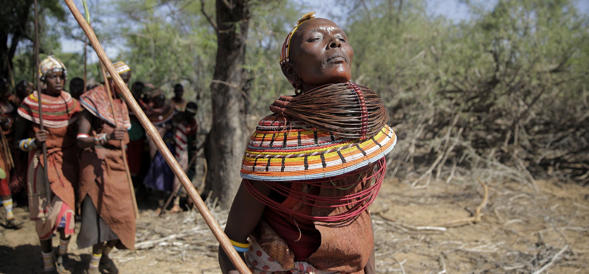Las mujeres Samburu cantan y bailan bajo un árbol mientras hacen una peregrinación diaria a un embalse donde derraman leche sobre el paisaje reseco como ofrenda el lunes 14 de noviembre de 2022, en el condado de Samburu, Kenia. Realizan esta ceremonia todos los días hasta que llega la lluvia.