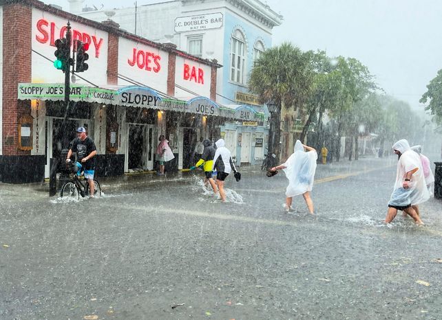 Determinados visitantes se animan a cruzar la calle Duval de Miami este martes cuando el tiempo ha empeorado.