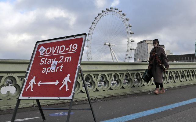 Una mujer camina sobre el puente de Westminster