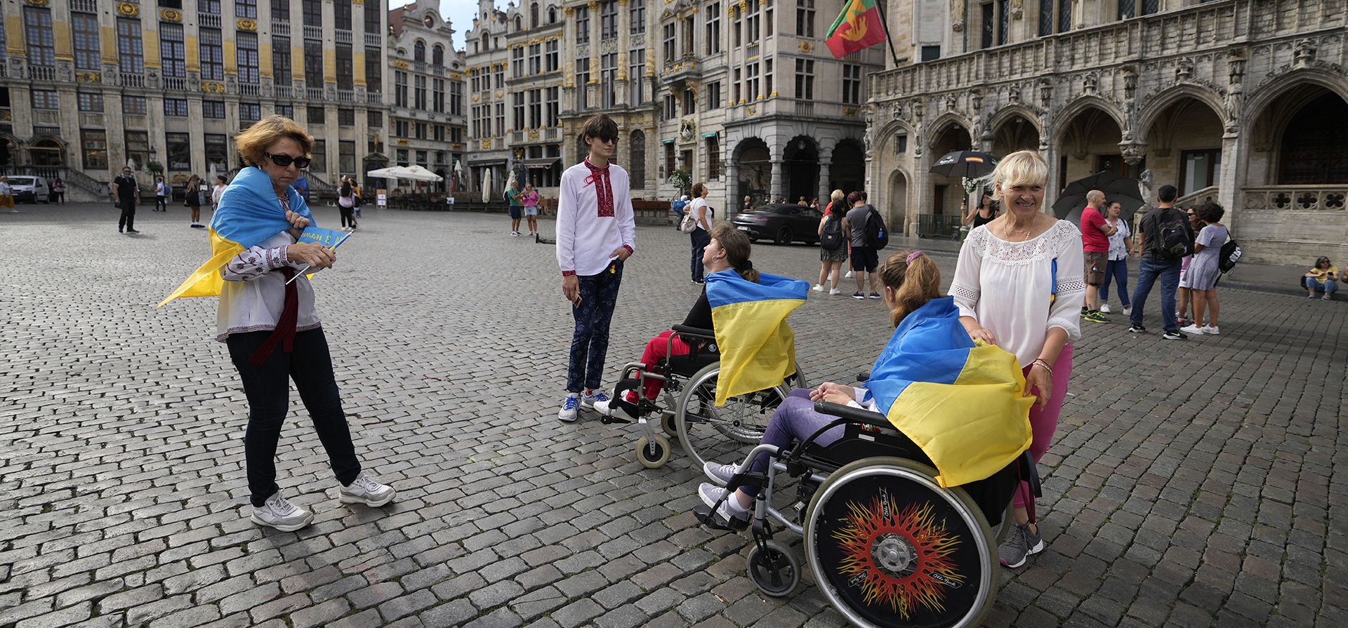 Una mujer ata una bandera ucraniana en la parte trasera de una silla de ruedas durante un evento por el Día de la Independencia de Ucrania en la histórica Grand Place de Bruselas, el miércoles 24 de agosto de 2022. Los líderes europeos prometen un apoyo inquebrantable a Ucrania mientras el país devastado por la guerra marca su Día de la Independencia.