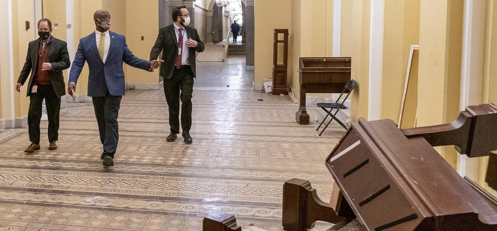 El senador Tim Scott, republicano por Carolina del Sur, segundo desde la izquierda, pasa frente a los daños en las primeras horas de la mañana del jueves 7 de enero de 2021, después de que los manifestantes irrumpieran en el Capitolio en Washington el miércoles 6 de Enero.