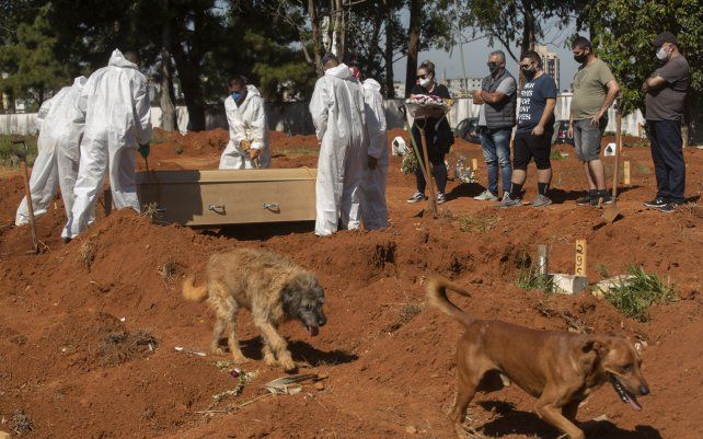 Trabajadores del cementerio de Sao Paulo realizan el entierro de una persona que murió por complicaciones relacionadas con el COVID-19 en el cementerio de Vila Formosa en Sao Paulo, Brasil, sus deudos despiden al fallecido.