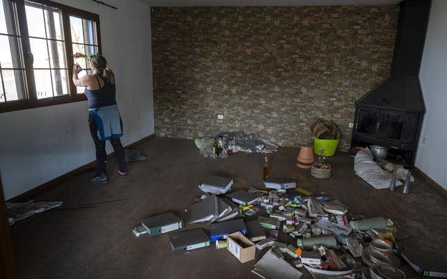 Cristina Vera cierra las ventanas de su casa cubierta de ceniza después de recoger sus última pertenencias en la isla canaria de La Palma