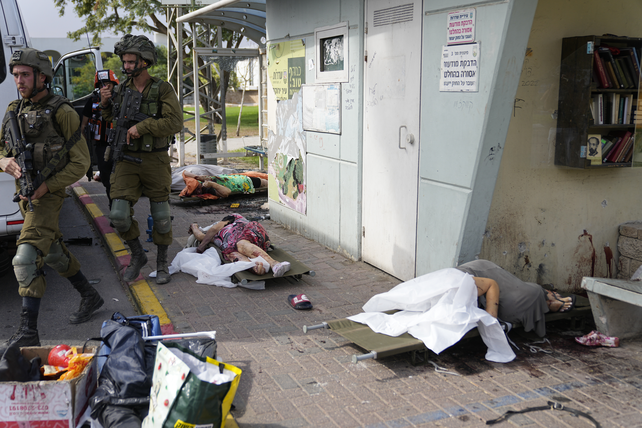 Soldados israelíes pasan entre cadáveres de los civiles asesinados por Hamás en Sderot.&nbsp;