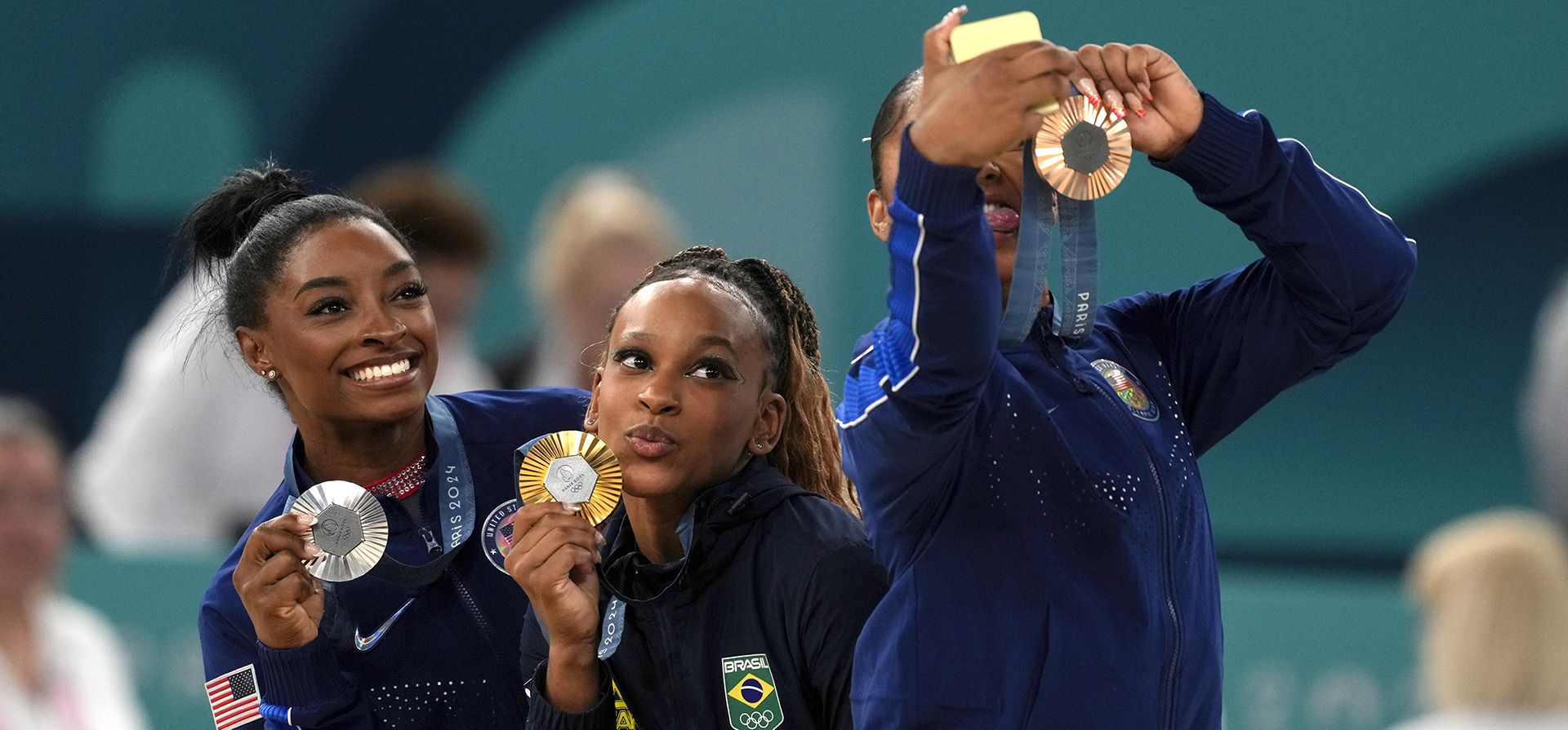 La medallista de oro Rebeca Andrade, en el centro, de Brasil, celebra en el podio con la medallista de plata Simone Biles, a la izquierda, de Estados Unidos, y Jordan Chiles, también de Estados Unidos, durante la ceremonia de entrega de medallas de la final individual de suelo de gimnasia artística femenina en la Arena Bercy de los Juegos Olímpicos de Verano de 2024, el lunes 5 de agosto de 2024, en París, Francia. (Foto AP/Francisco Seco)
