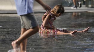 Una niña juega en una fuente pública en Milán.