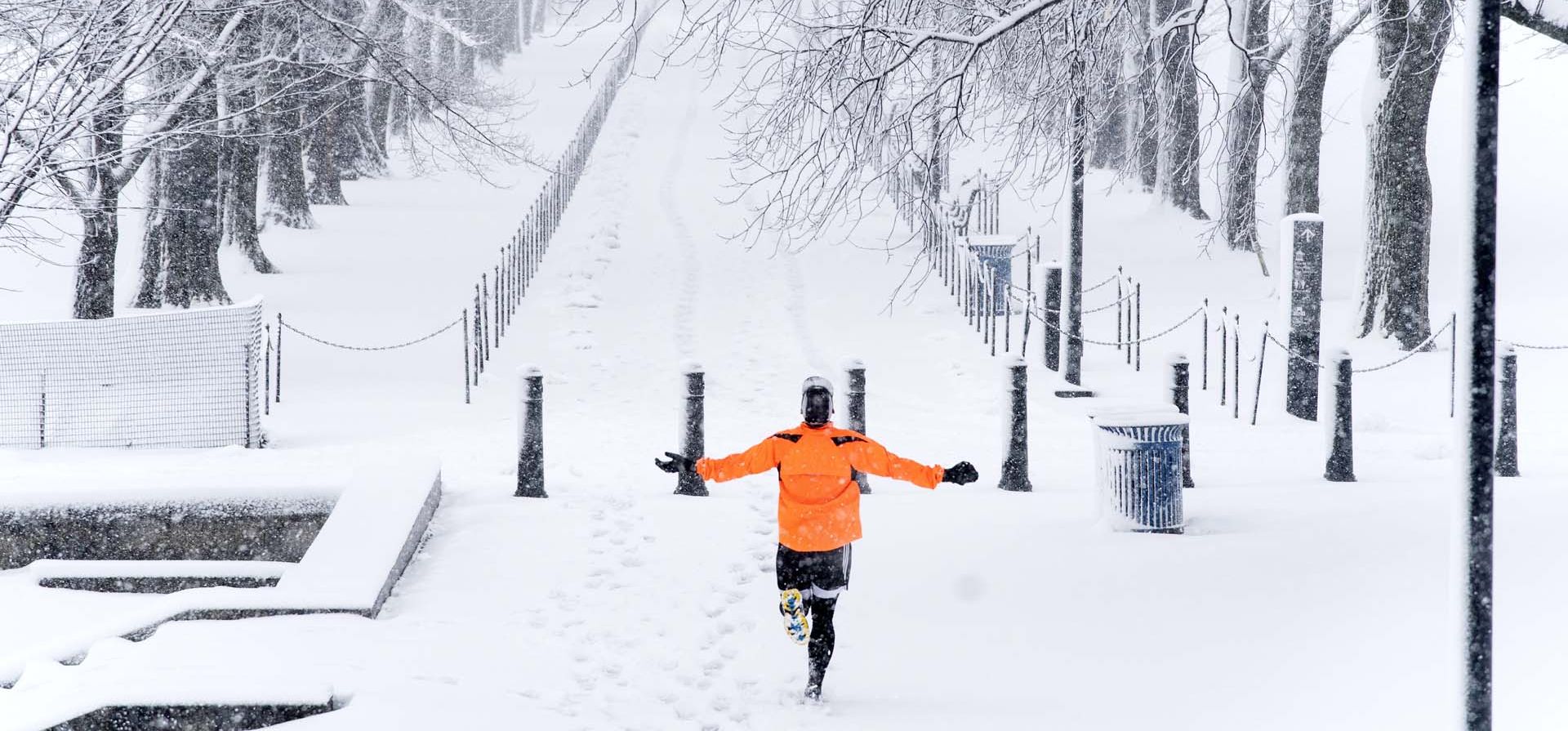 Un corredor se deleita con el momento mientras corre a lo largo de la Piscina Reflectante del Monumento a Lincoln mientras cae la nieve en Washington.