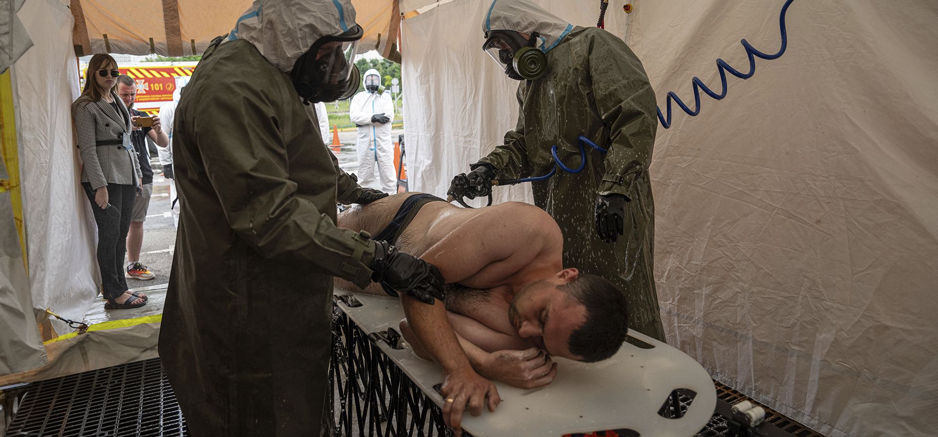 Trabajadores de emergencia ucranianos con trajes de protección contra la radiación desinfectan a un hombre durante un entrenamiento en Zaporizhzhia, Ucrania, el jueves 29 de junio de 2023. La planta de energía nuclear de Zaporizhzhia, la más grande de Europa, depende en gran parte del agua del depósito que ahora se está vaciando en Kakhovka. (Foto AP/Evgeniy Maloletka) Trabajadores de emergencia ucranianos con trajes de protección contra la radiación desinfectan a un hombre durante un entrenamiento en Zaporizhzhia, Ucrania, el jueves 29 de junio de 2023. La planta de energía nuclear de Zaporizhzhia, la más grande de Europa, depende en gran parte del agua del depósito que ahora se está vaciando en Kakhovka. (Foto AP/Evgeniy Maloletka)