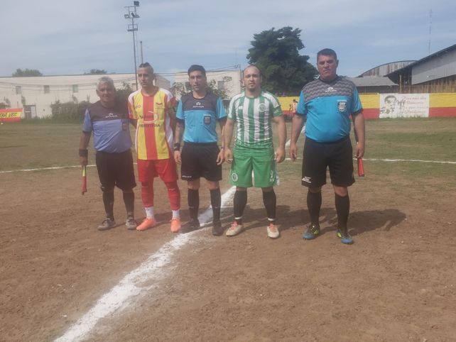 La previa en barrio Ludueña. Los capitanes y la terna arbitral posan para la foto. 