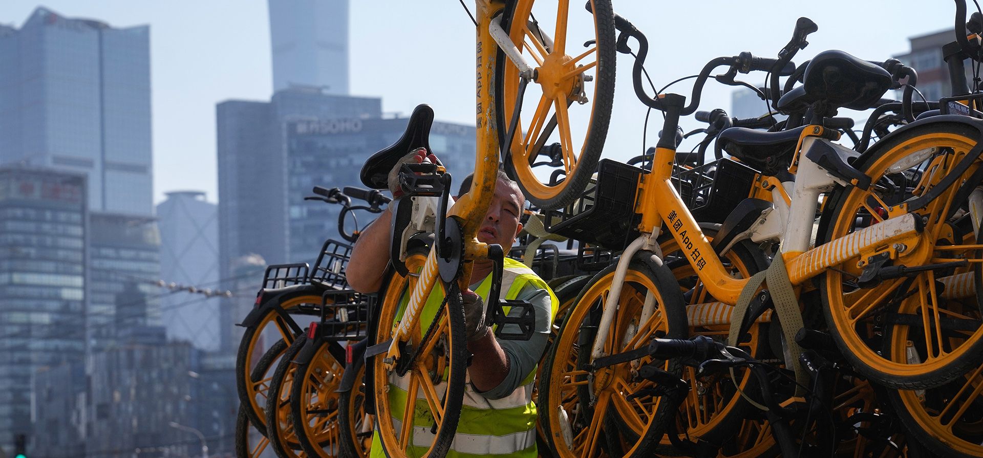 Un trabajador se baja de la bicicleta de una empresa de bicicletas compartidas en una calle frente al distrito comercial central de Beijing, el lunes 24 de octubre de 2022. El crecimiento económico de China se aceleró en el último trimestre, pero aún se encontraba entre los más débiles en décadas, ya que el Partido Comunista gobernante.