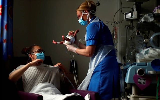 Una enfermera neonatal entrega al bebé prematuro a su madre