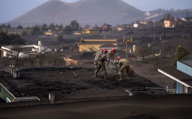 Soldados del ejército español retiran la ceniza del techo de una casa mientras el volcán continúa en erupción en la isla canaria de La Palma. El volcán en erupción continuó emitiendo gran cantidad de magma