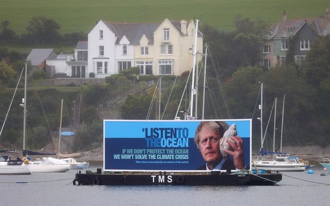 Una pancarta de protesta desplegada sobre una balsa en Falmouth Bay. Fotografía: Tom Nicholson / Reuters