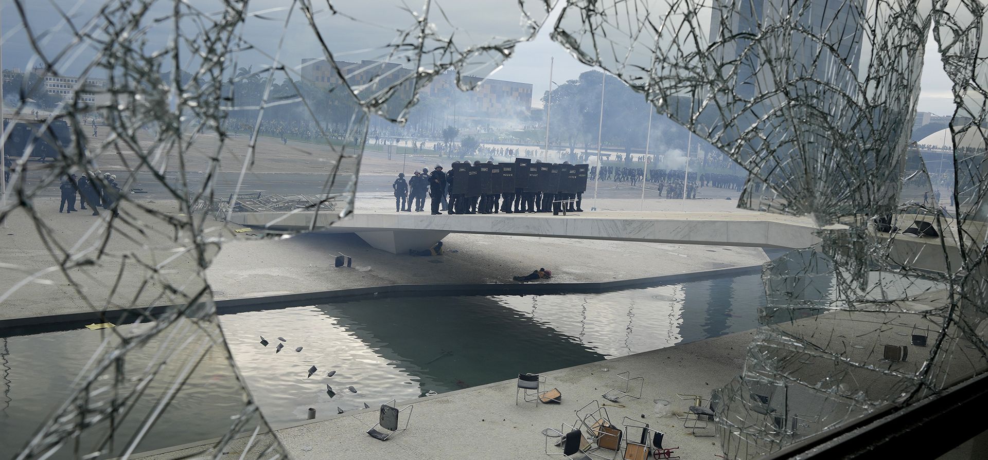 La policía con equipo antidisturbios se ve a través de una ventana rota mientras se forman frente al Palacio de Planalto después de que los manifestantes, partidarios del expresidente de Brasil, Jair Bolsonaro, irrumpieron en el Palacio en Brasilia, Brasil, el domingo 8 de enero de 2023. (Foto AP/Eraldo Peres)