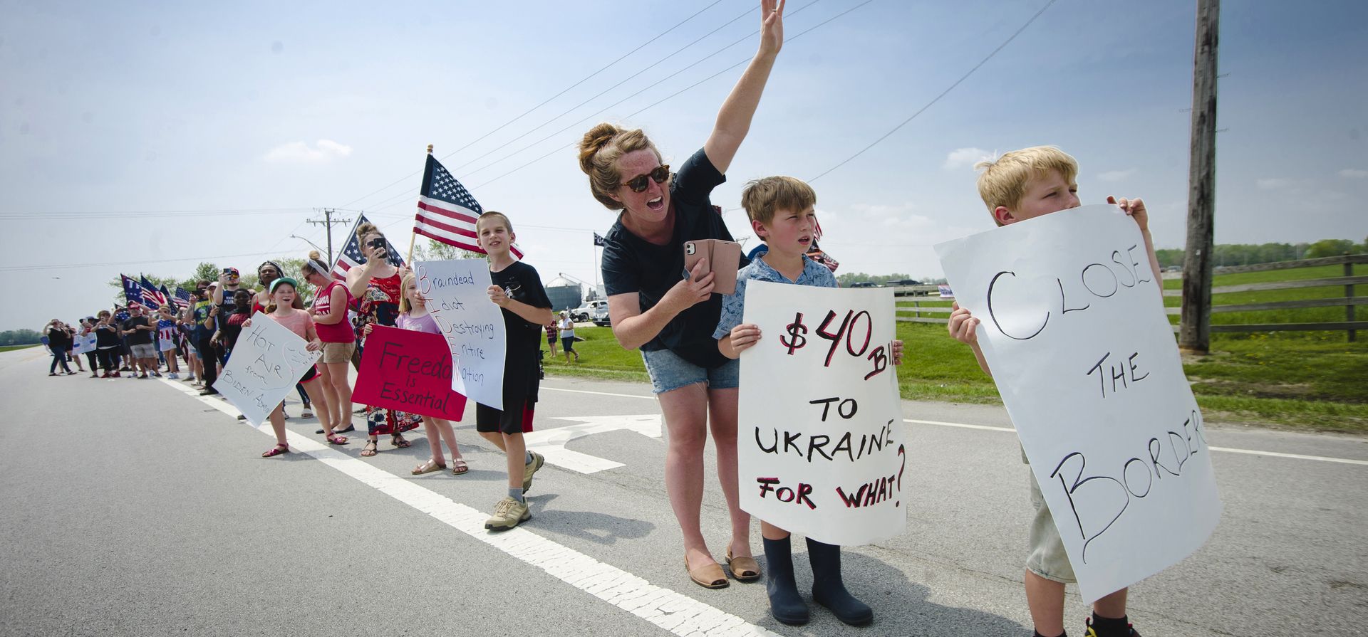 Nicole Neesby, de Washington, Iowa, y sus hijos Emmett, de 9 años, y Gideon, de 7, a la derecha, se unen a una protesta por la llegada del presidente Joe Biden a Kankakee, Illinois, el miércoles 11 de mayo de 2022.
