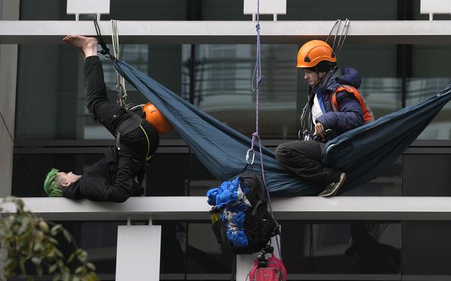 Un oficial de policía desciende en rápel hacia un manifestante ambiental