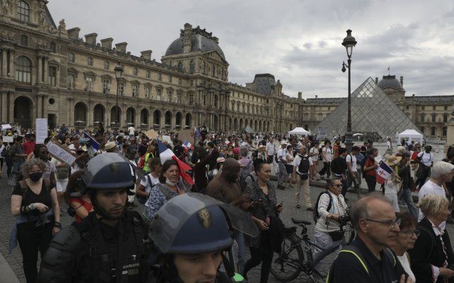 Manifestantes marchan en el patio del museo del Louvre contra el pase de salud, en París. La gente se opone al pase de salud COVID-19 necesario para acceder a restaurantes, trenes de larga distancia y otros lugares.