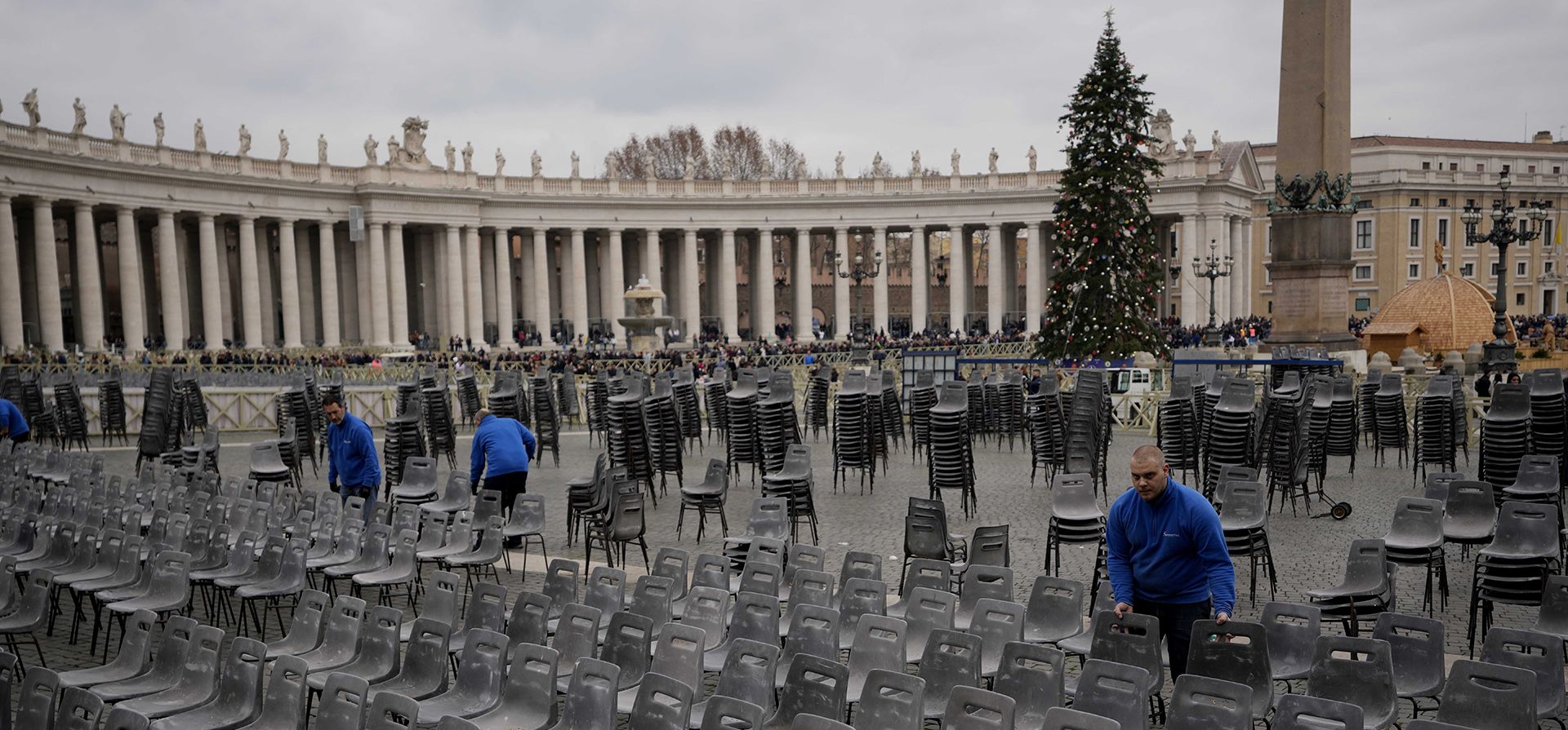Trabajadores colocan sillas mientras la gente hace fila para ingresar a la Basílica de San Pedro en el Vaticano, donde el difunto Papa Benedicto XVI será enterrado en el Vaticano, el lunes 2 de enero de 2023. Benedicto XVI, el teólogo alemán que será recordado como el el primer Papa en 600 años en renunciar, murió el sábado, anunció el Vaticano. Tenía 95 años. (Foto AP/Ben Curtis)