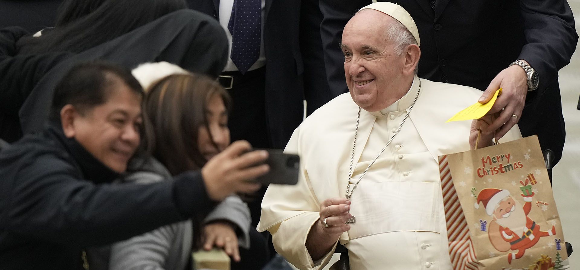 La gente se toma selfies cuando el papa Francisco se va después de su audiencia general semanal en el Aula Pablo VI, en el Vaticano, el miércoles 21 de diciembre de 2022. (Foto AP/Andrew Medichini)