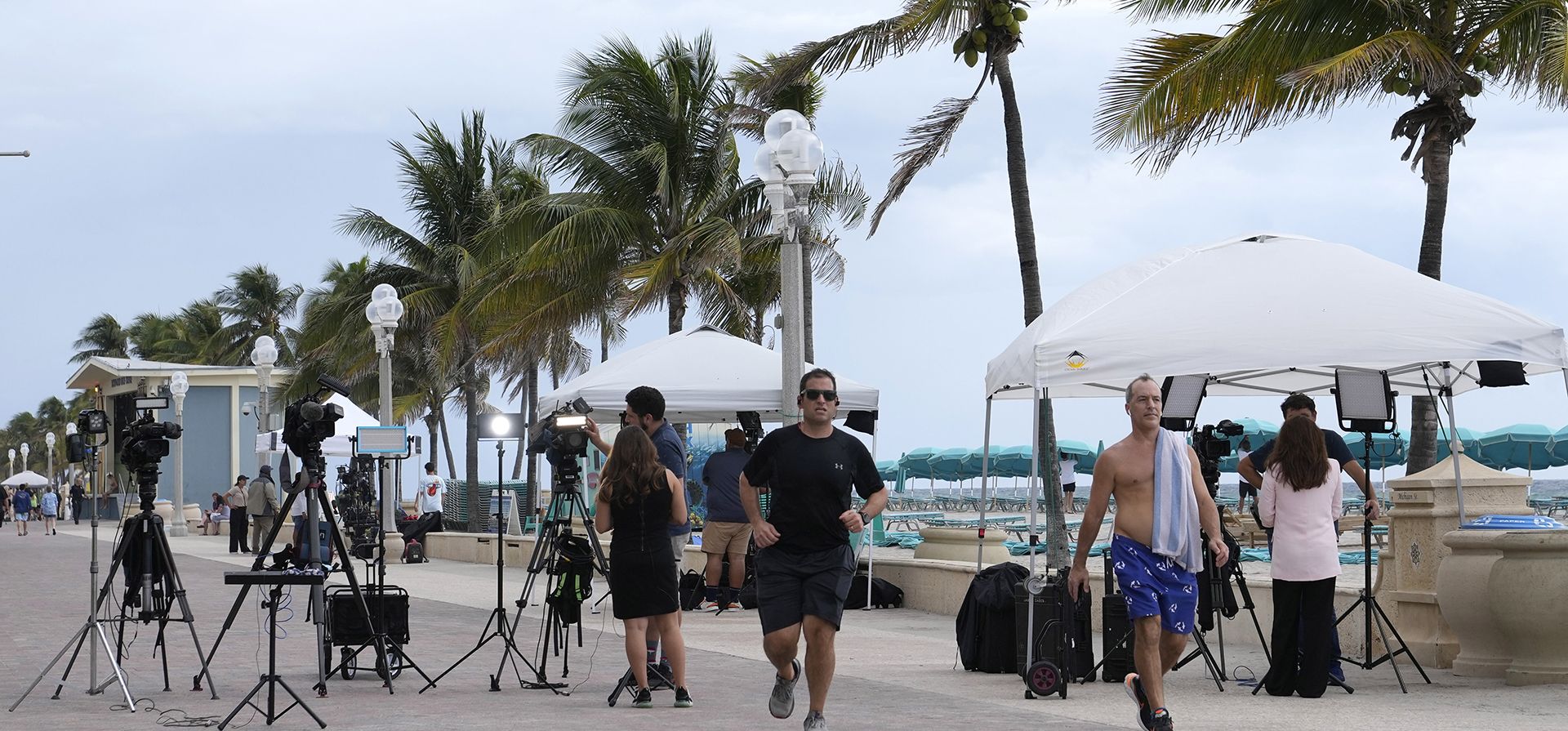 La gente pasa frente a los equipos de noticias de televisión cerca de la escena de un tiroteo a lo largo de Hollywood Broadwalk, el martes 30 de mayo de 2023, en Hollywood, Florida. Nueve personas resultaron heridas cuando estallaron disparos a lo largo del paseo marítimo, en el Día de los Caídos. (Foto AP/Lynne Sladky) La gente pasa frente a los equipos de noticias de televisión cerca de la escena de un tiroteo a lo largo de Hollywood Broadwalk, el martes 30 de mayo de 2023, en Hollywood, Florida. Nueve personas resultaron heridas cuando estallaron disparos a lo largo del paseo marítimo, en el Día de los Caídos. (Foto AP/Lynne Sladky)