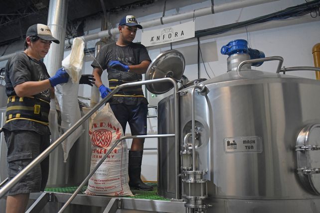 Dos operarios frente a los barriles fermentadores de la planta rosarina elaboradora de la cerveza Ánfora.