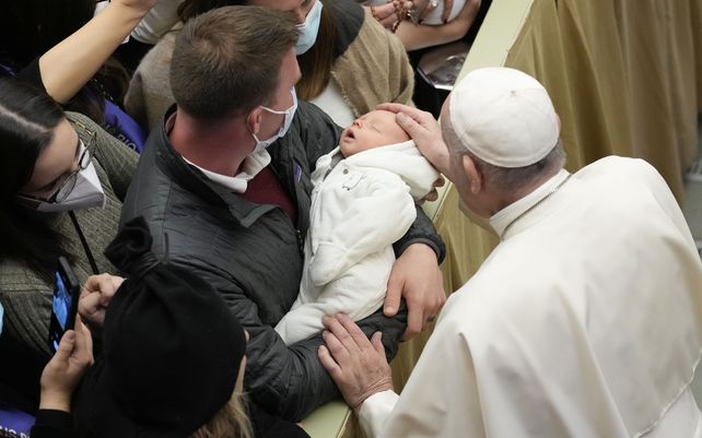El Papa Francisco acaricia a un bebé mientras saluda a los fieles al final de su audiencia general semanal en el Salón Pablo VI del Vaticano