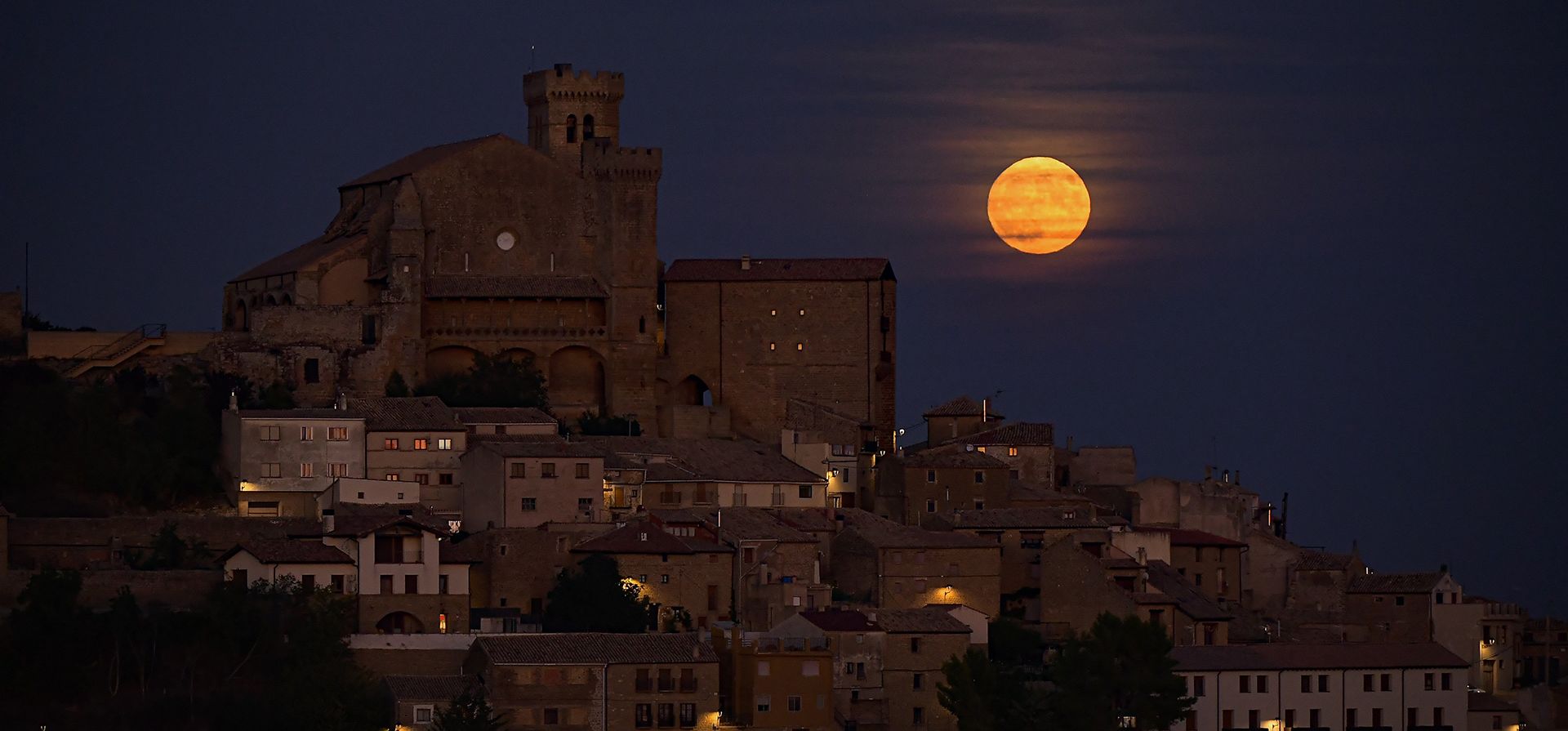 La luna conocida como luna azul sale detrás del pequeño pueblo de Ujue, al norte de España, el miércoles 30 de agosto de 2023. (Foto AP/Álvaro Barrientos)
