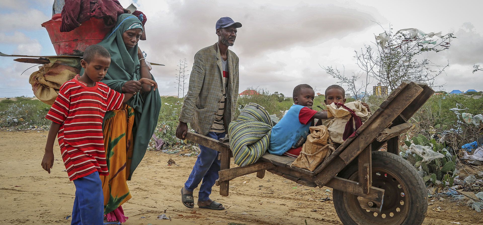 Un residente local usa una carretilla para transportar a los niños de una mujer que huyó de las zonas afectadas por la sequía para llegar a un campamento improvisado para desplazados en las afueras de Mogadiscio, Somalia. Por la guerra en Ucrania se ha cortado abruptamente la ayuda de millones de dólares para la crisis humanitaria más prolongada, Somalia es quizás una de las naciones más vulnerable, ya que miles mueren de hambre en medio de la peor sequía en décadas.