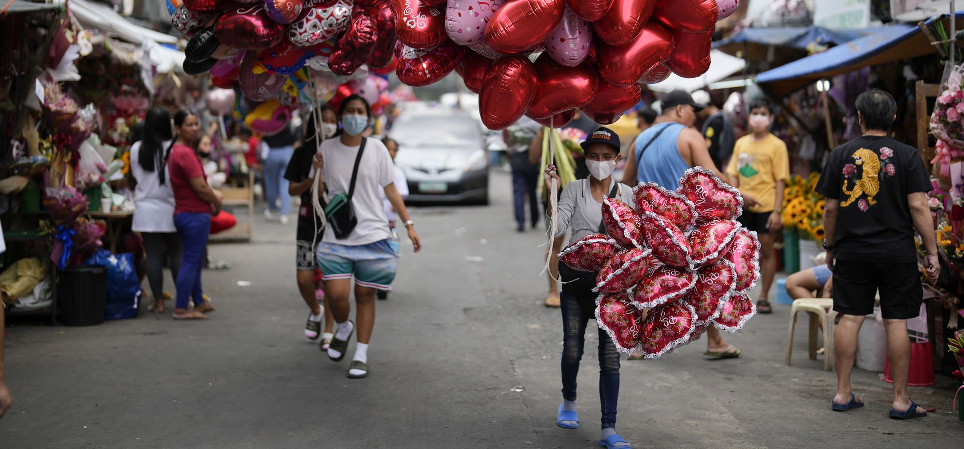 Mujeres venden globos con forma de corazón en un mercado de flores en Manila, Filipinas, el lunes 13 de febrero de 2023. Los precios de las flores han aumentado debido a la gran demanda un día antes del Día de San Valentín. (Foto AP/Aarón Favila)