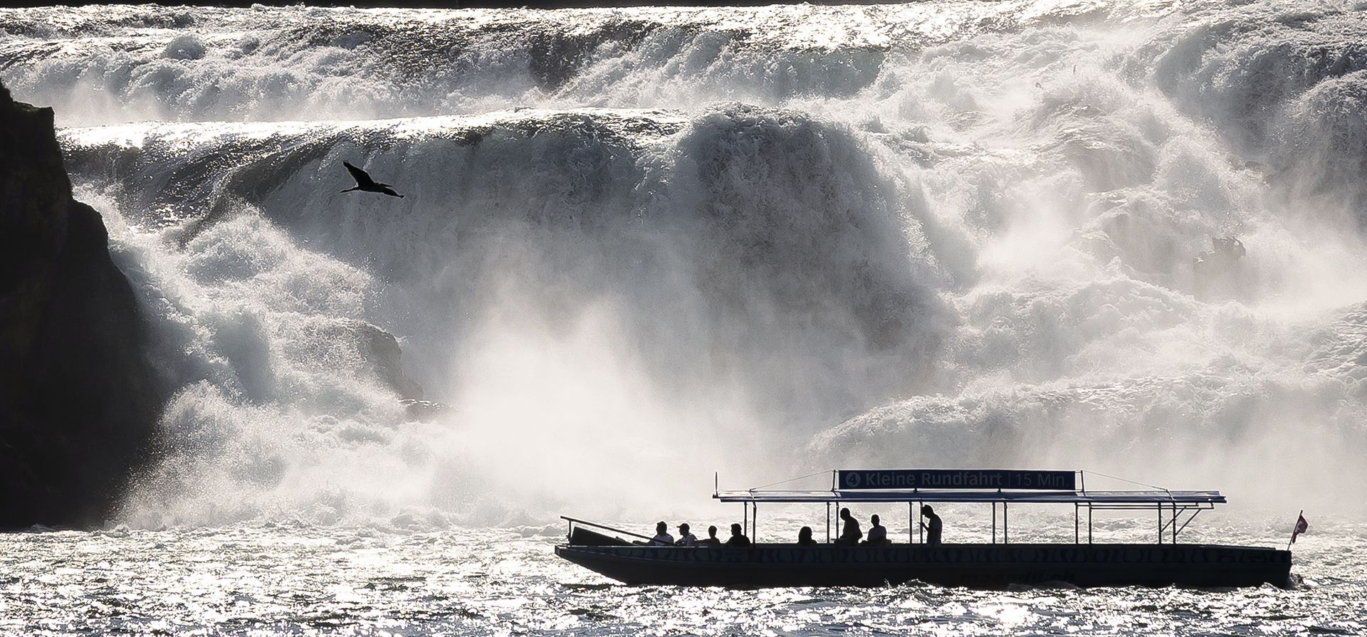 Un barco turístico navega frente a las cataratas del Rin en Neuhausen, Suiza, el viernes 5 de agosto de 2022.