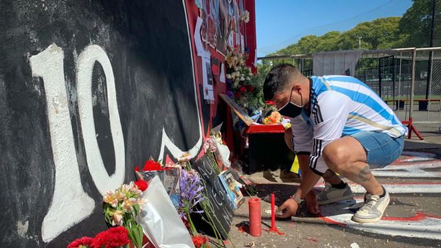 Un hincha con la camiseta de la selección argentina deja una ofrenda en el mural con la imagen de Diego Maradona.