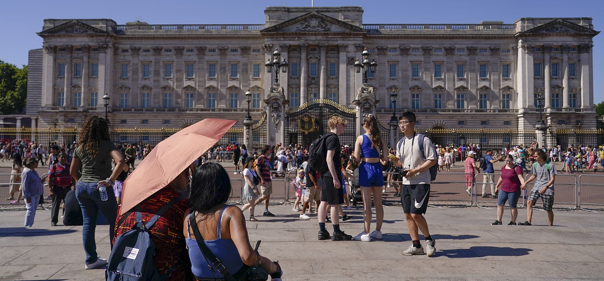 Los turistas se refugian del sol bajo una sombrilla mientras se sientan en las escaleras del Queen Victoria Memorial, en Londres, el jueves 11 de agosto de 2022. Las olas de calor y el clima seco prolongado están dañando los paisajes, los jardines y la vida silvestre, advirtió el National Trust.