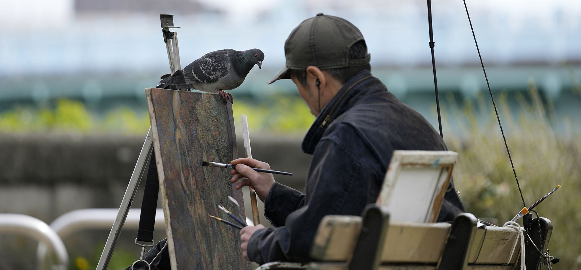 Una paloma se posa sobre un lienzo mientras un pintor dibuja la naturaleza en Tokio, el jueves 7 de abril de 2022.