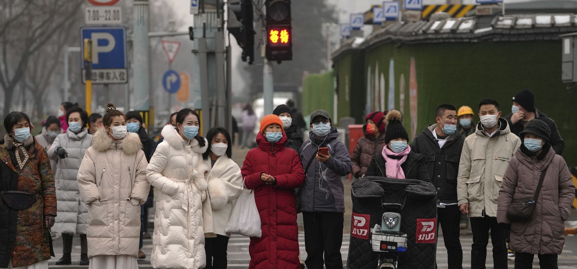Peatones esperan para cruzar una intersección en el Distrito Comercial Central de Beijing, el lunes 24 de enero de 2022. Un nuevo brote en Beijing ha llevado a las autoridades a evaluar a millones e imponer nuevas medidas dos semanas antes de la apertura de los Juegos Olímpicos de Invierno.
