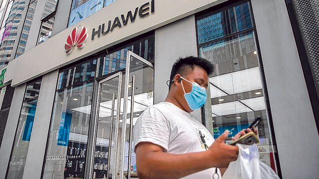 Un ciudadano chino chequea su celular mientras traspone un local de Huawei en Beijing.