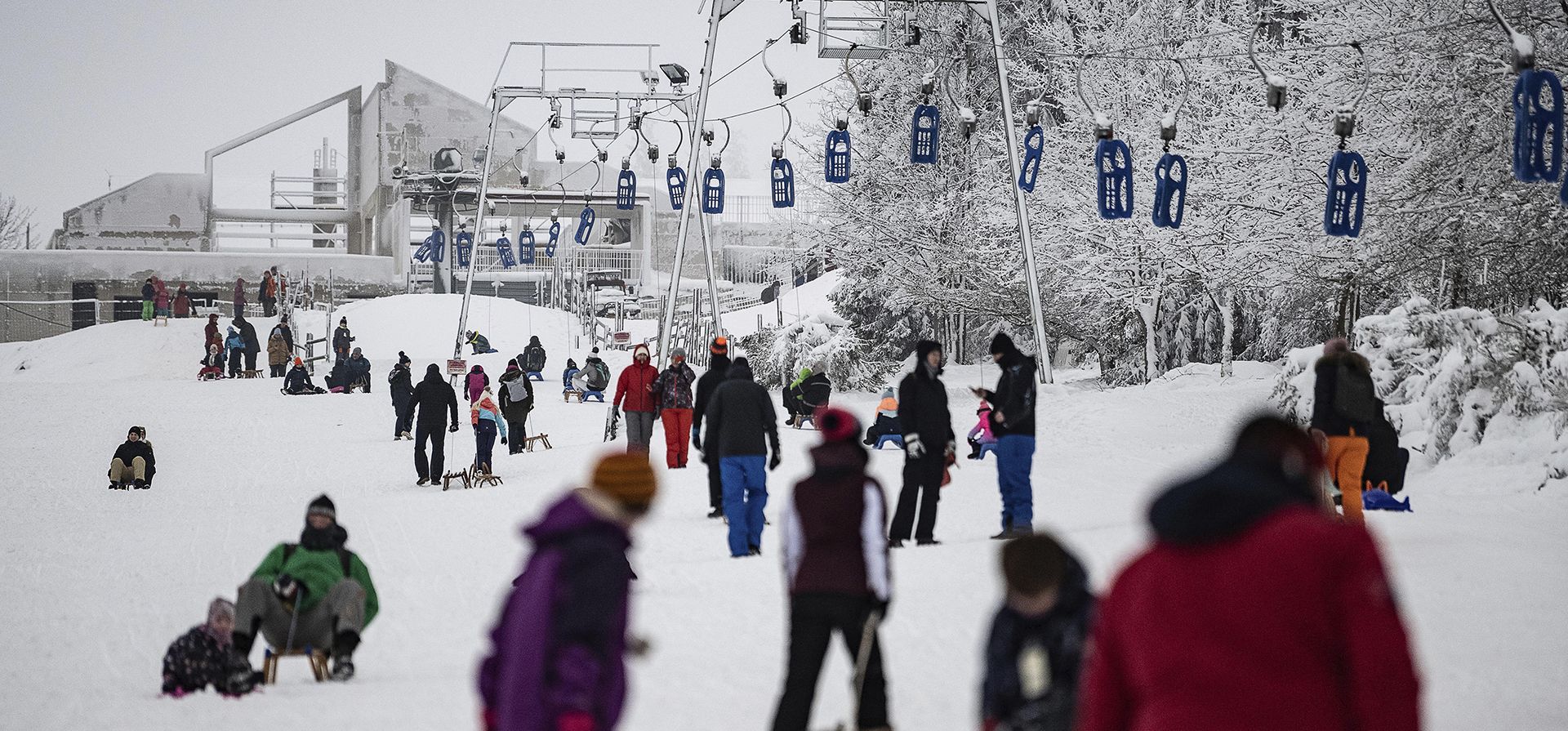La gente camina con sus trineos a lo largo de un tobogán en las montañas Harz en el último día de vacaciones en Torfhaus, Alemania, el martes 31 de enero de 2023. (Swen Pfoertner/dpa vía AP)