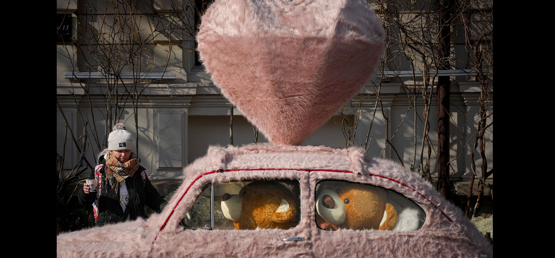 Una mujer camina junto a un automóvil decorado con pieles y ositos de peluche en Bucarest, Rumania, el martes 14 de febrero de 2023.  (Foto AP/Andreea Alexandru)