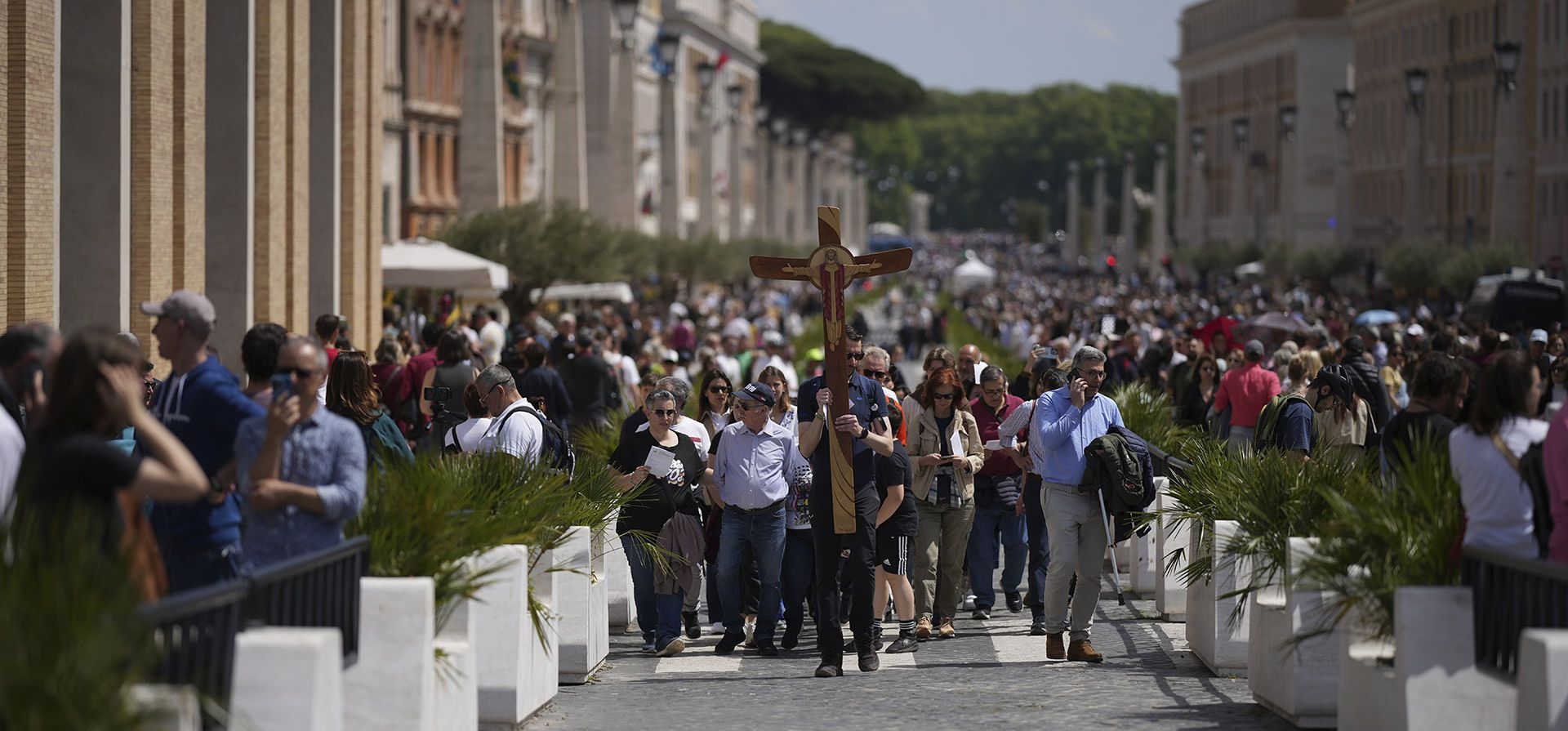 Un hombre es seguido por fieles mientras sostiene una cruz junto a la Plaza de San Pedro en el Vaticano después de que el cardenal camarlengo Kevin Joseph Farrell anunciara la muerte del papa Francisco, el lunes 21 de abril de 2025. (Foto AP/Andrew Medichini)