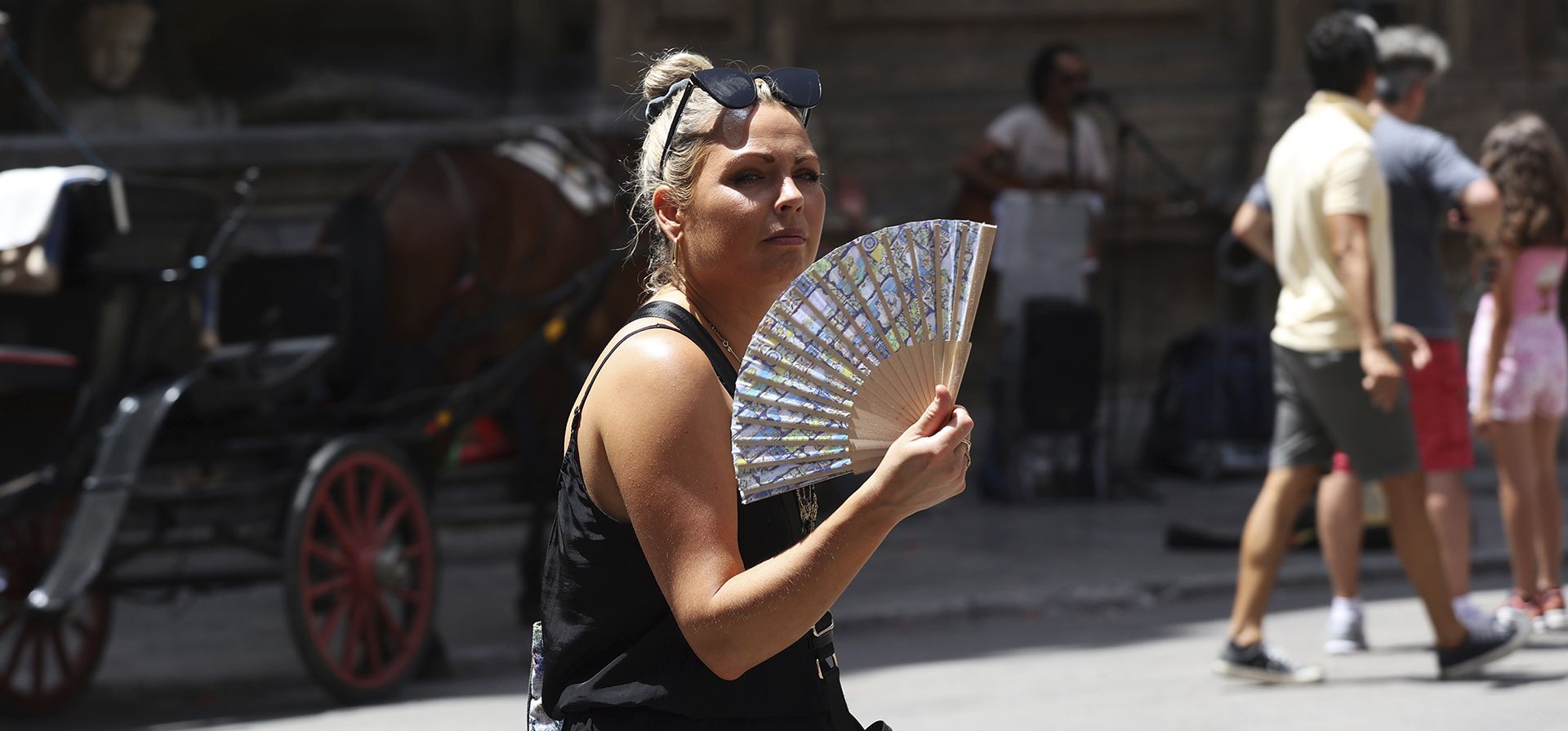 Una turista usa un abanico plegable mientras visita Palermo, Sicilia, durante un día caluroso con temperaturas de más de 40º grados. Se espera que las temperaturas alcancen nuevos máximos históricos esta semana. (Alberto Lo Bianco/LaPresse vía AP)