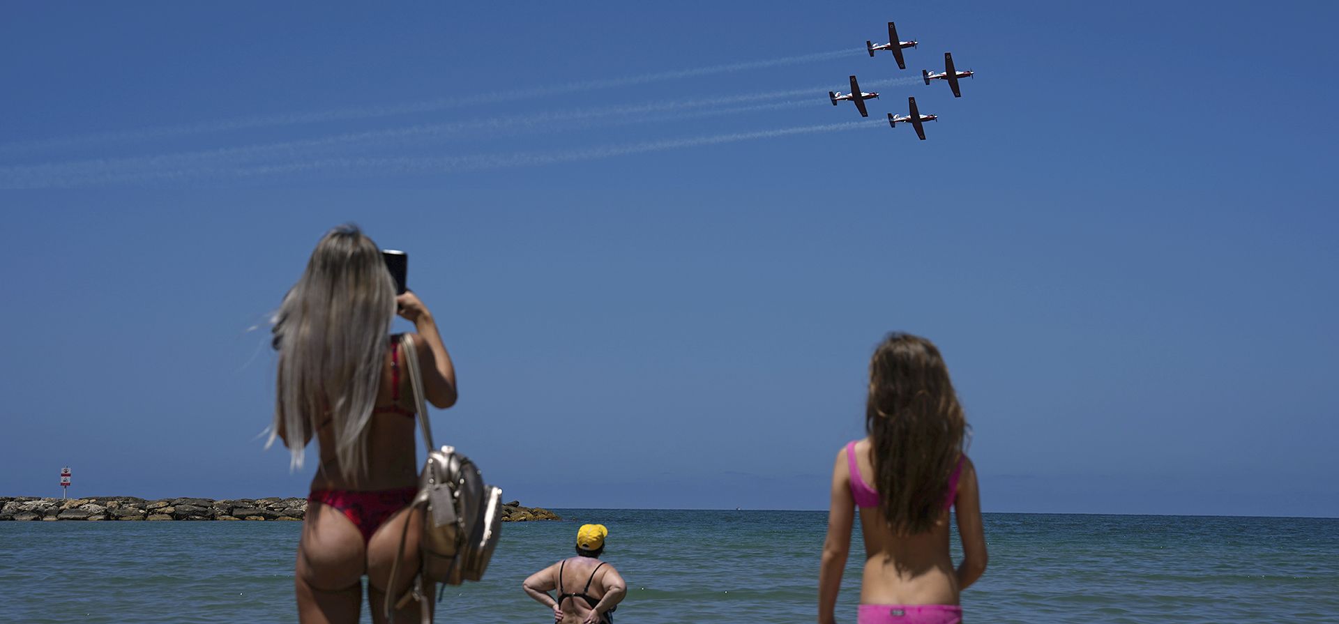 Un equipo acrobático de la Fuerza Aérea de Israel vuela en formación sobre los bañistas en el mar Mediterráneo durante un ensayo antes del 75º Día de la Independencia de Israel en Tel Aviv, Israel, el lunes 24 de abril de 2023. (Foto AP/Ariel Schalit)