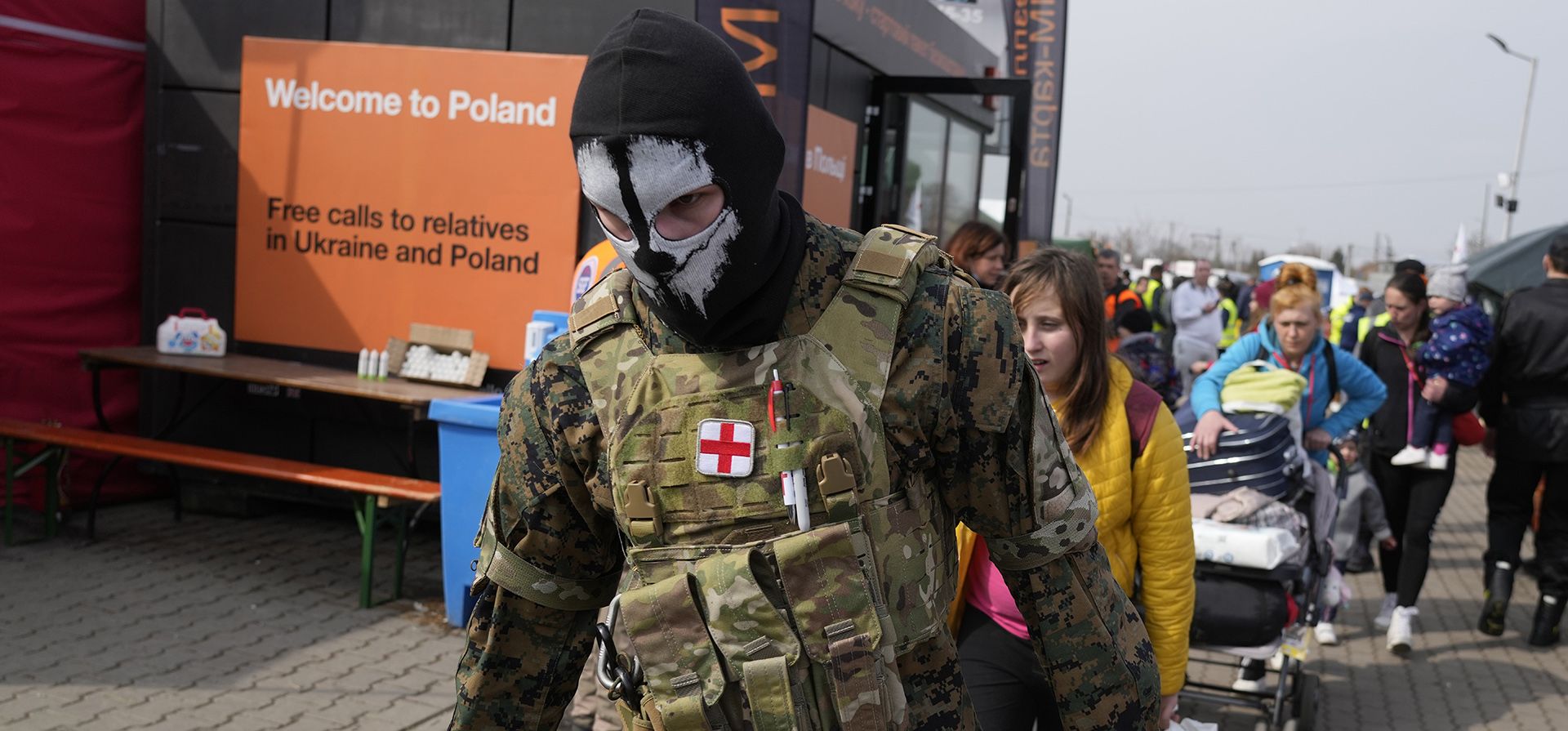 Un militar lleva bolsas mientras los refugiados ucranianos salen del cruce fronterizo en Medyka, sureste de Polonia, el miércoles 30 de marzo de 2022. Tras el anuncio de Rusia de que las tropas podrían retirarse de varias partes de Ucrania, algunos refugiados ucranianos están regresando a su país.