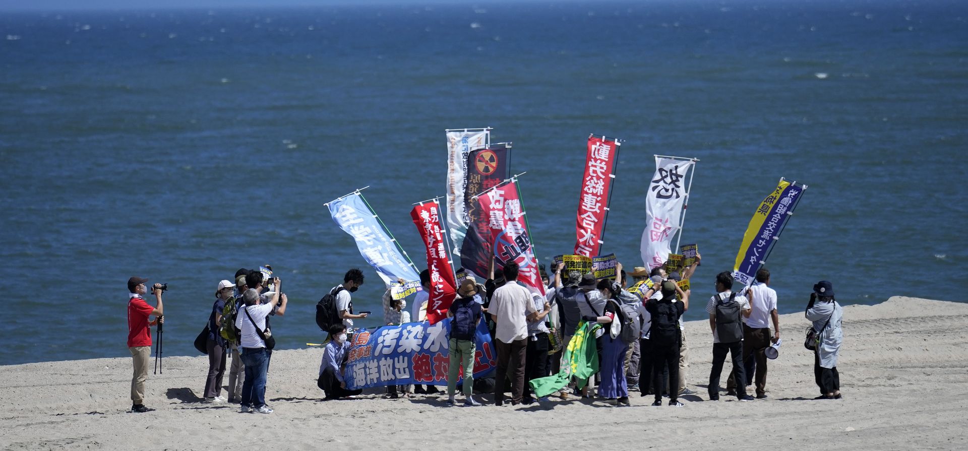 La gente protesta en una playa hacia la planta de energía nuclear de Fukushima Daiichi, dañada por un enorme terremoto y tsunami el 11 de marzo de 2011, en la ciudad de Namie, noreste de Japón, el jueves 24 de agosto de 2023. La pancarta, que se ve a la derecha, dice: Oponerse a la liberación del agua radiactiva tratada al océano. (Foto AP/Eugene Hoshiko) (Foto AP/Eugene Hoshiko) La gente protesta en una playa hacia la planta de energía nuclear de Fukushima Daiichi, dañada por un enorme terremoto y tsunami el 11 de marzo de 2011, en la ciudad de Namie, noreste de Japón, el jueves 24 de agosto de 2023. La pancarta, que se ve a la derecha, dice: Oponerse a la liberación del agua radiactiva tratada al océano. (Foto AP/Eugene Hoshiko) (Foto AP/Eugene Hoshiko)
