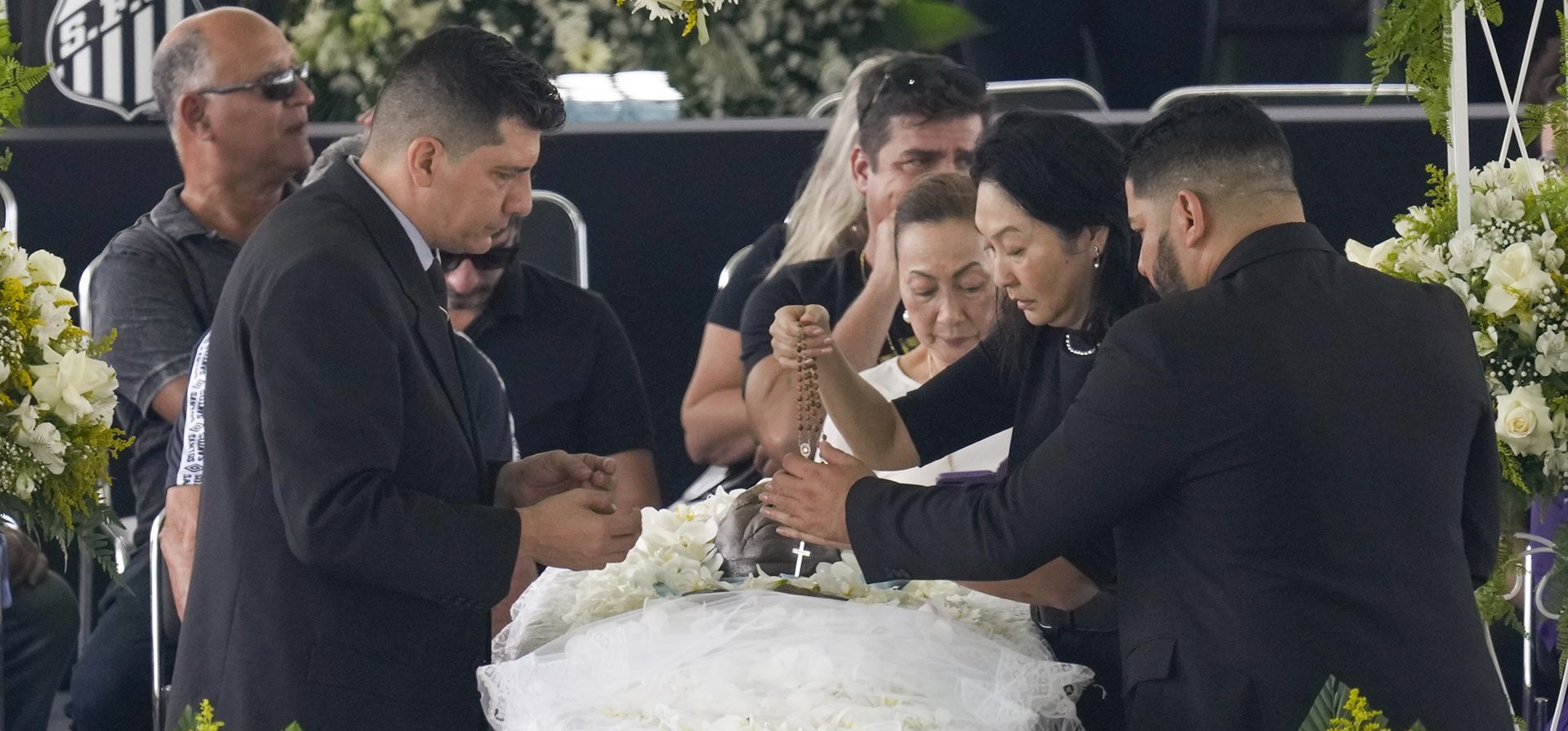 Marcia Aoki, la viuda del fallecido gran futbolista brasileño Pelé, sostiene un rosario sobre su cuerpo que yace en el estadio Vila Belmiro durante su velatorio en Santos, Brasil, el lunes 2 de enero de 2023. (AP Foto/Andre Penner)